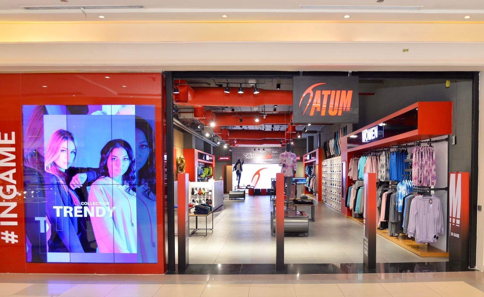 the inside of a clothing store with a red wall and a large window with a picture of a woman on it