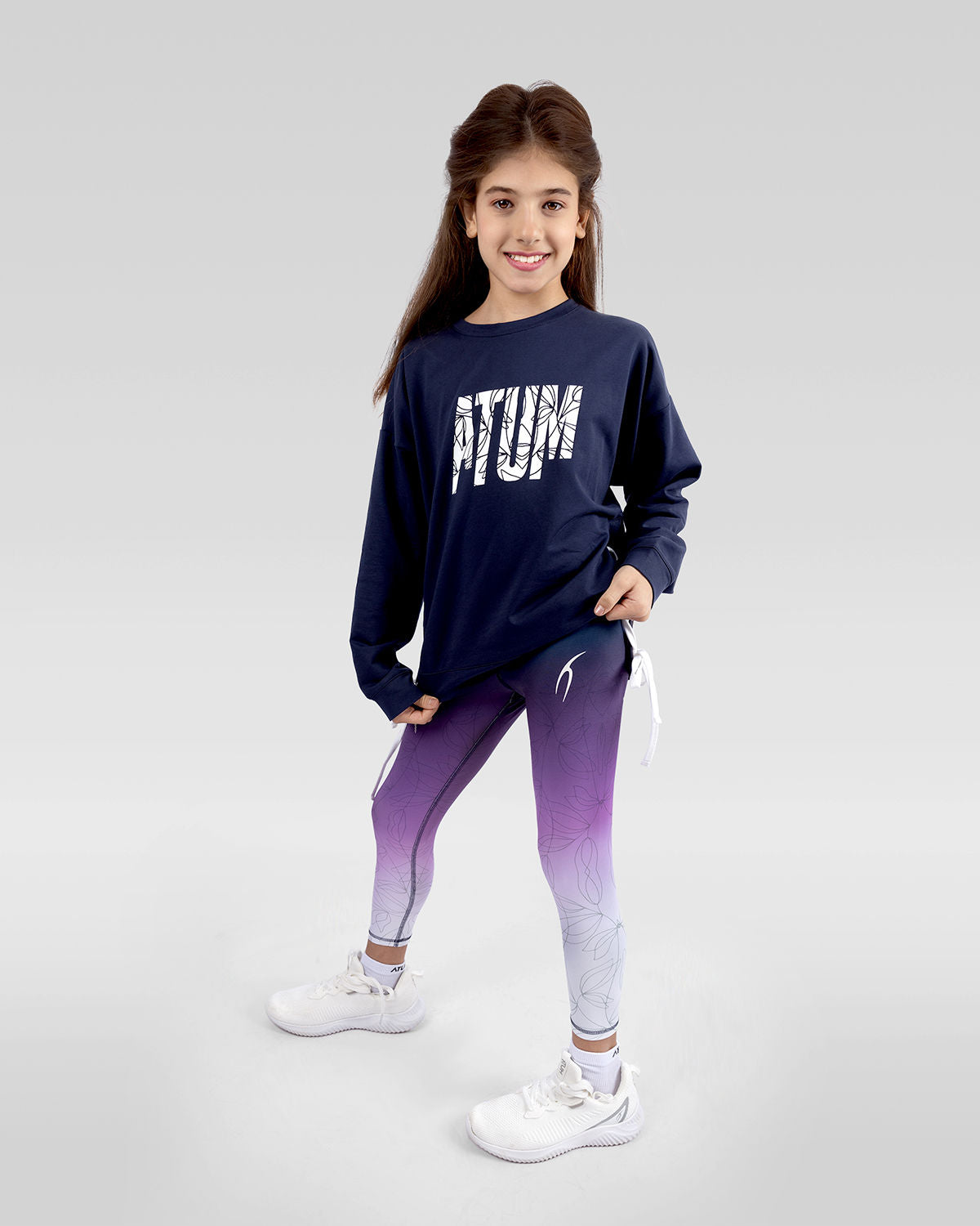 Photo by ð—”ð—§ð—¨ð— SPORTSWEAR Â® on December 20, 2022. May be an image of 1 girl wears navy sweatshirt, violet leggings and white shoes with printed Atum.